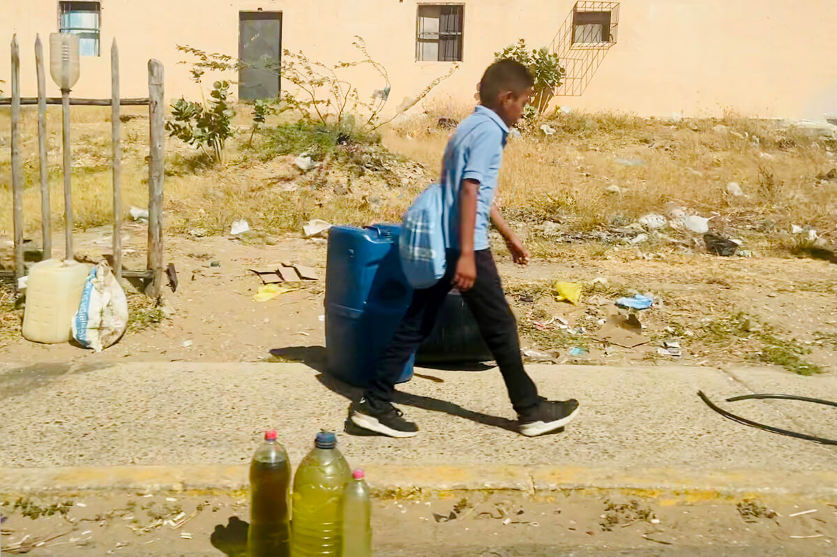 Niño camina por una calle de Zulia, Venezuela, donde se ven algunas botellas con gasolina ilegal